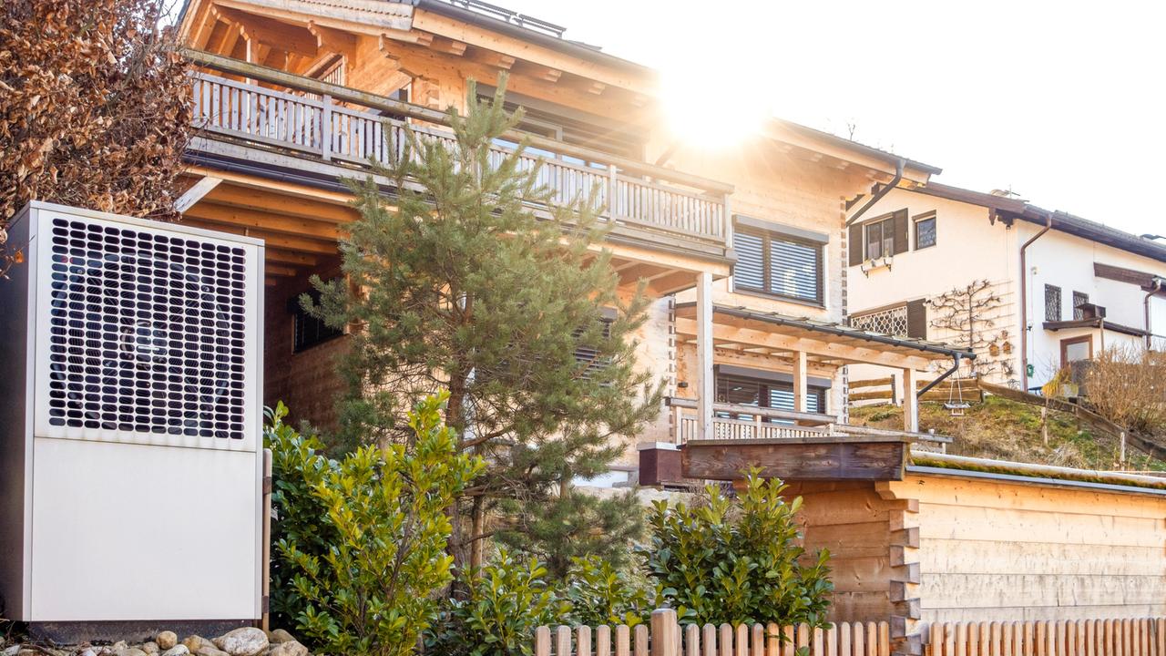 Eine Wärmepumpe vor einem bayerischen Holzhaus
