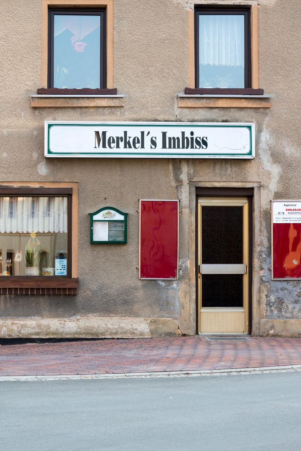 An einer Hauswand in Mylau hängt ein Schild mit der Aufschrift "Merkel`s Imbiss".