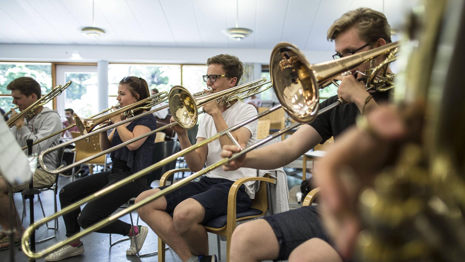 Eine Gruppe von Jungen und Mädchen bilden ein Bläser-Ensemble, das gerade konzentriert übt. Eine Gruppe von Jungen und Mädchen bilden ein Bläser-Ensemble, das gerade konzentriert übt.