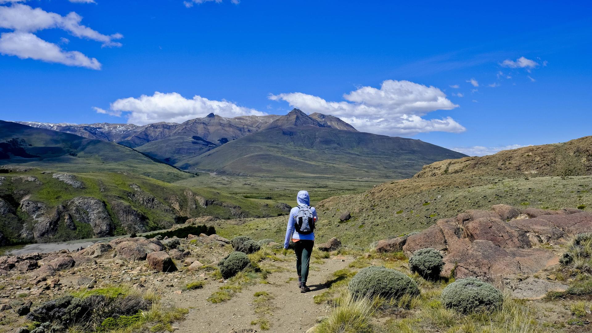 Eine Backpackerin im blauen Anorak wandert durch die Berge in Patagonien, Argentinien. Eine Backpackerin im blauen Anorak wandert durch die Berge in Patagonien, Argentinien.