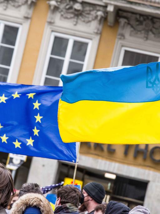 Auf einer Demonstration sind die europäische und die ukrainische Flagge zu sehen.