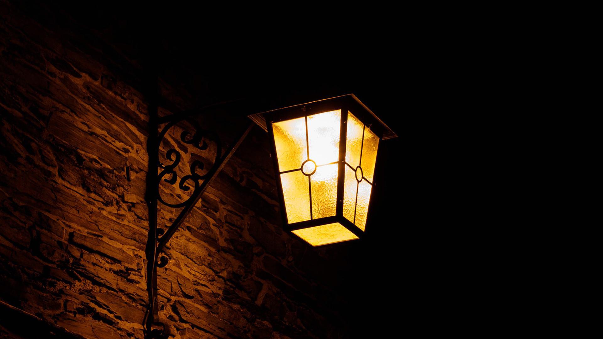 Eine leuchtende Laterne an einer Wand in der Nacht. 