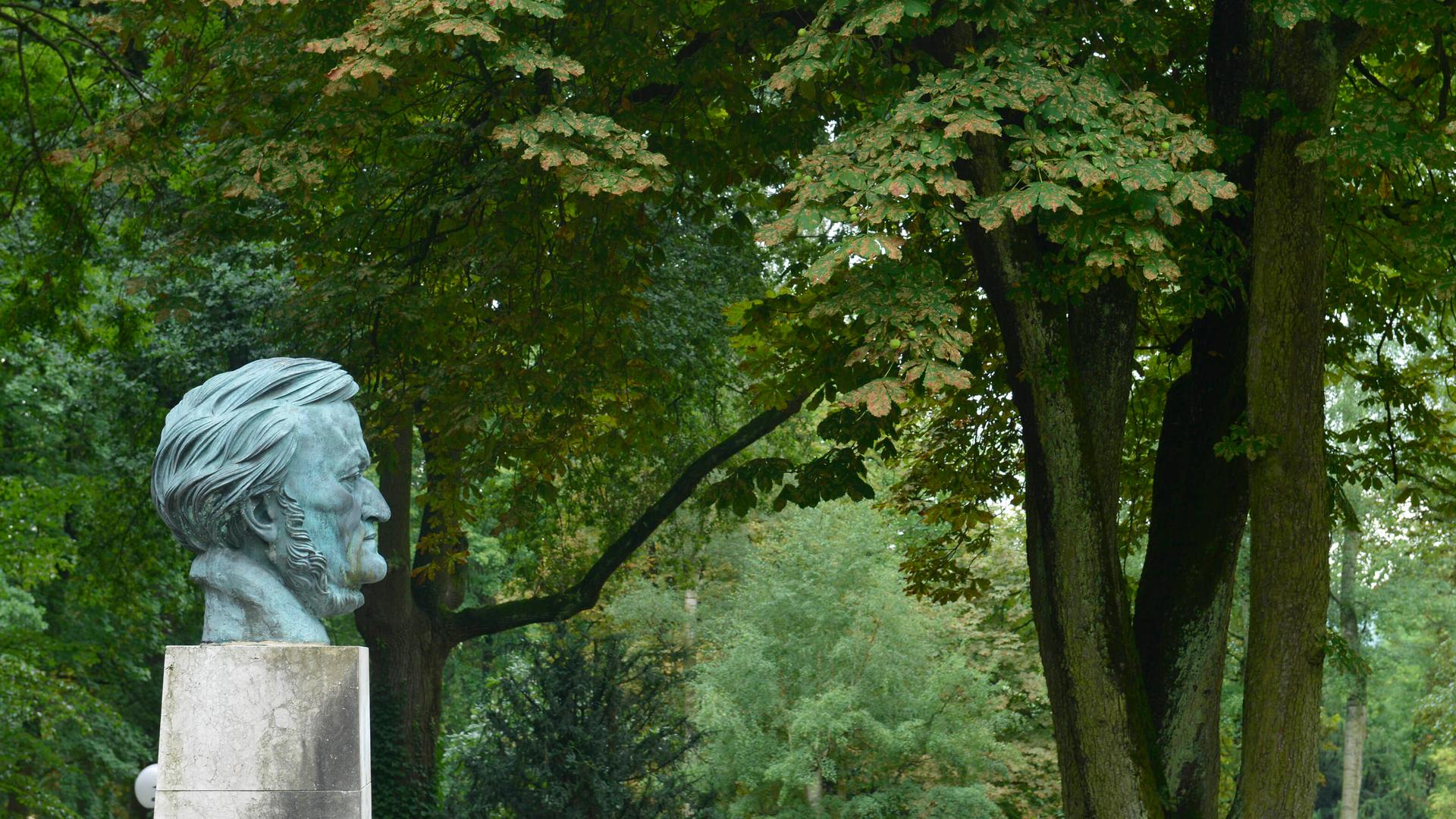 Blick auf die Büste Richard Wagners auf dem Festspielhügel in Bayreuth von der Seite, im Hintergrund große, alte Kastanienbäume. Blick auf die Büste Richard Wagners auf dem Festspielhügel in Bayreuth von der Seite, im Hintergrund große, alte Kastanienbäume.
