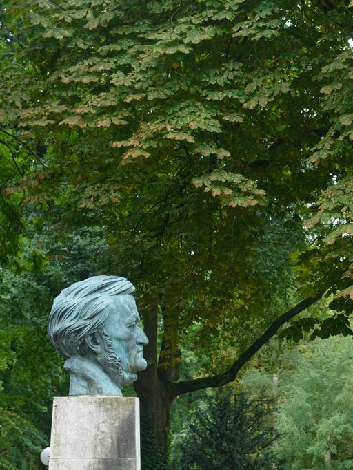 Blick auf die Büste Richard Wagners auf dem Festspielhügel in Bayreuth von der Seite, im Hintergrund große, alte Kastanienbäume.