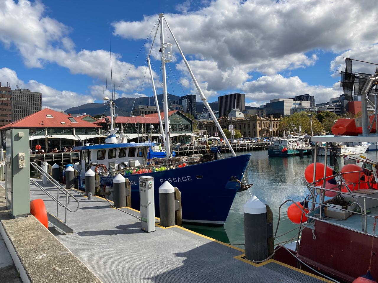In einem kleinen Hafen liegen einige Schiffe, im Hintergrund normale Häuser neben Hochhäusern. In einem kleinen Hafen liegen einige Schiffe, im Hintergrund normale Häuser neben Hochhäusern.