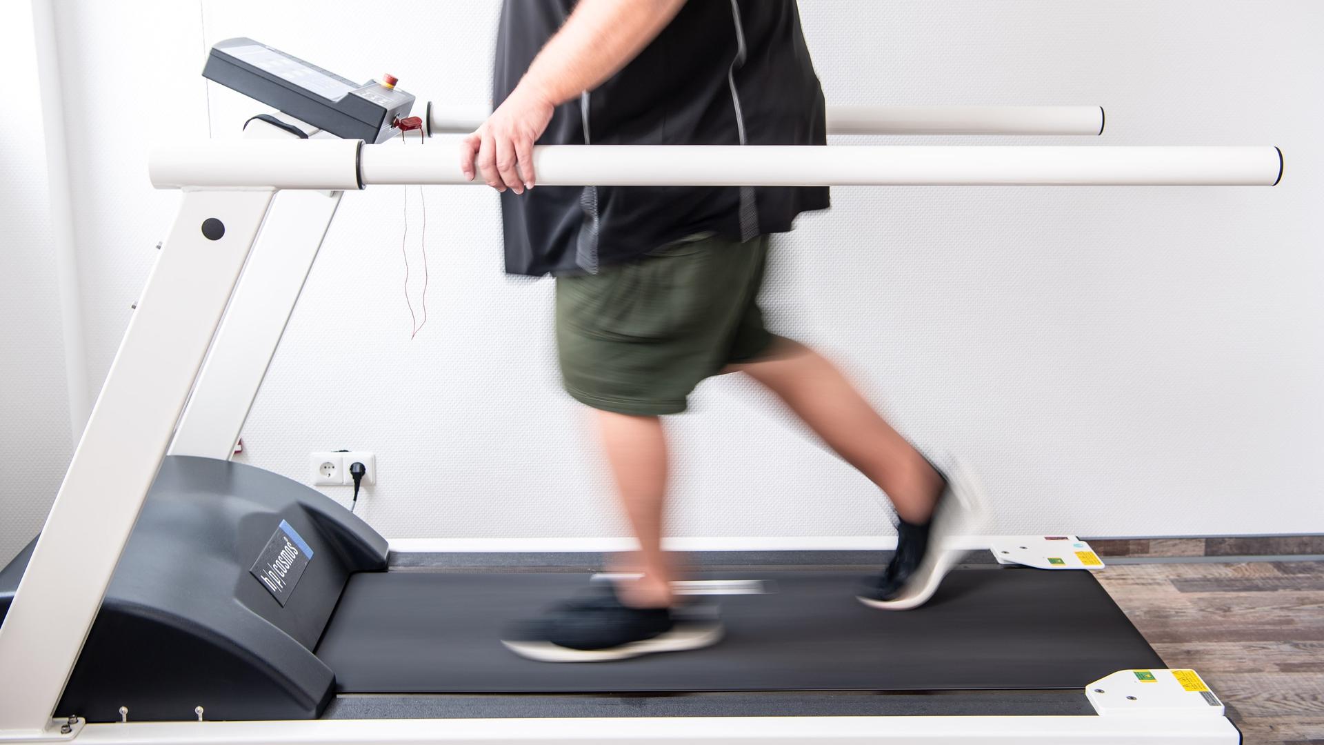 Ein Mann trainiert an einem Laufband um seine Ausdauer nach einer Coronainfektion zu stärken. Ein Mann trainiert an einem Laufband um seine Ausdauer nach einer Coronainfektion zu stärken.