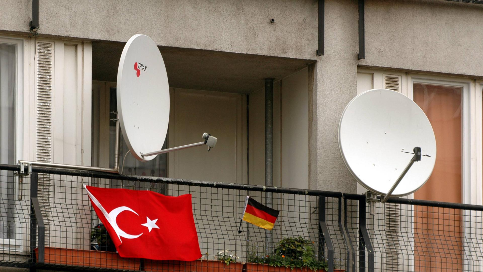 Satellitenschüsseln auf einem Balkon mit deutscher und türkischer Flagge. Satellitenschüsseln auf einem Balkon mit deutscher und türkischer Flagge.