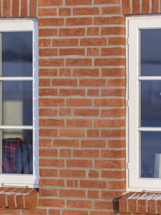 Gemütliches Barnstedt: Junge Frau sitzt auf einem Fensterbrett mit Wolldecke und Kaffeetasse in der Hand