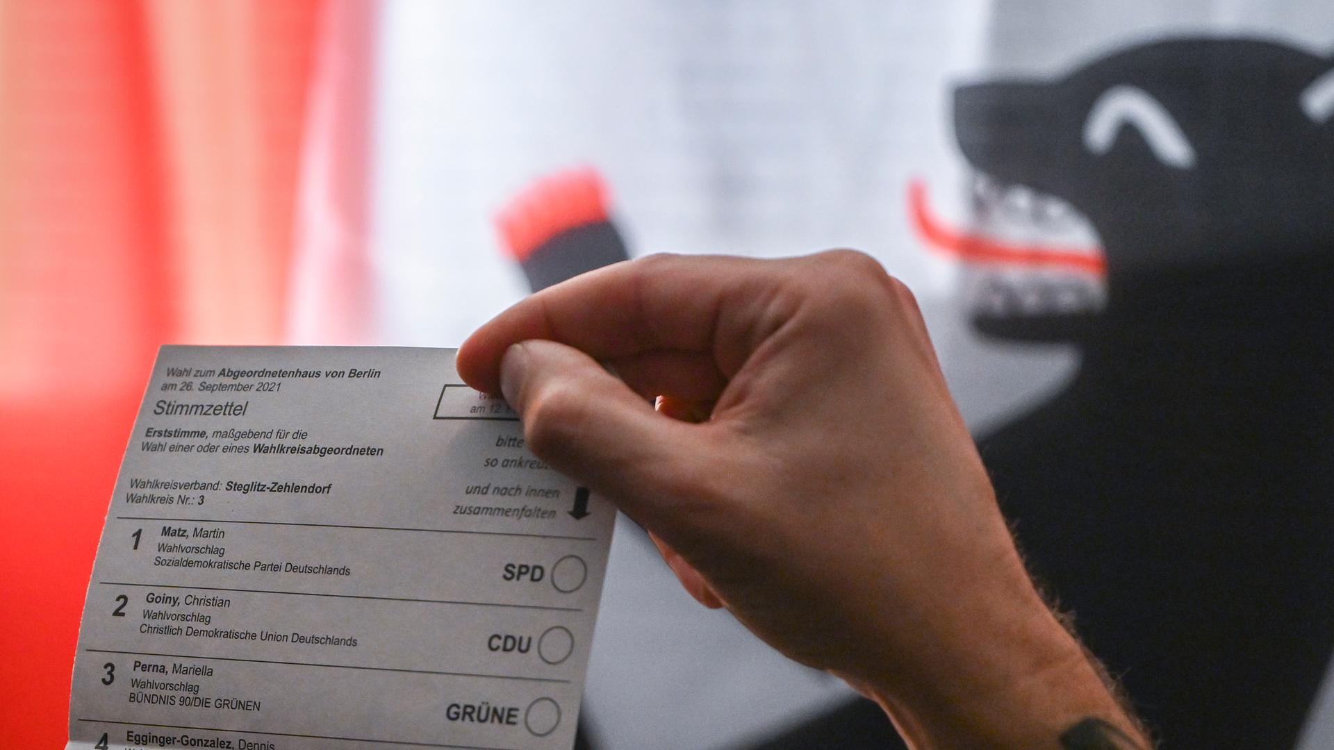 Ein Mann hält den Stimmzettel für die Erststimme in den Händen. 