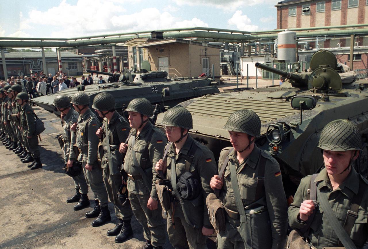 Soldaten stehen vor einem Industriegebäude, vor dem drei NVA-Schützenpanzer stehen. Soldaten stehen vor einem Industriegebäude, vor dem drei NVA-Schützenpanzer stehen.