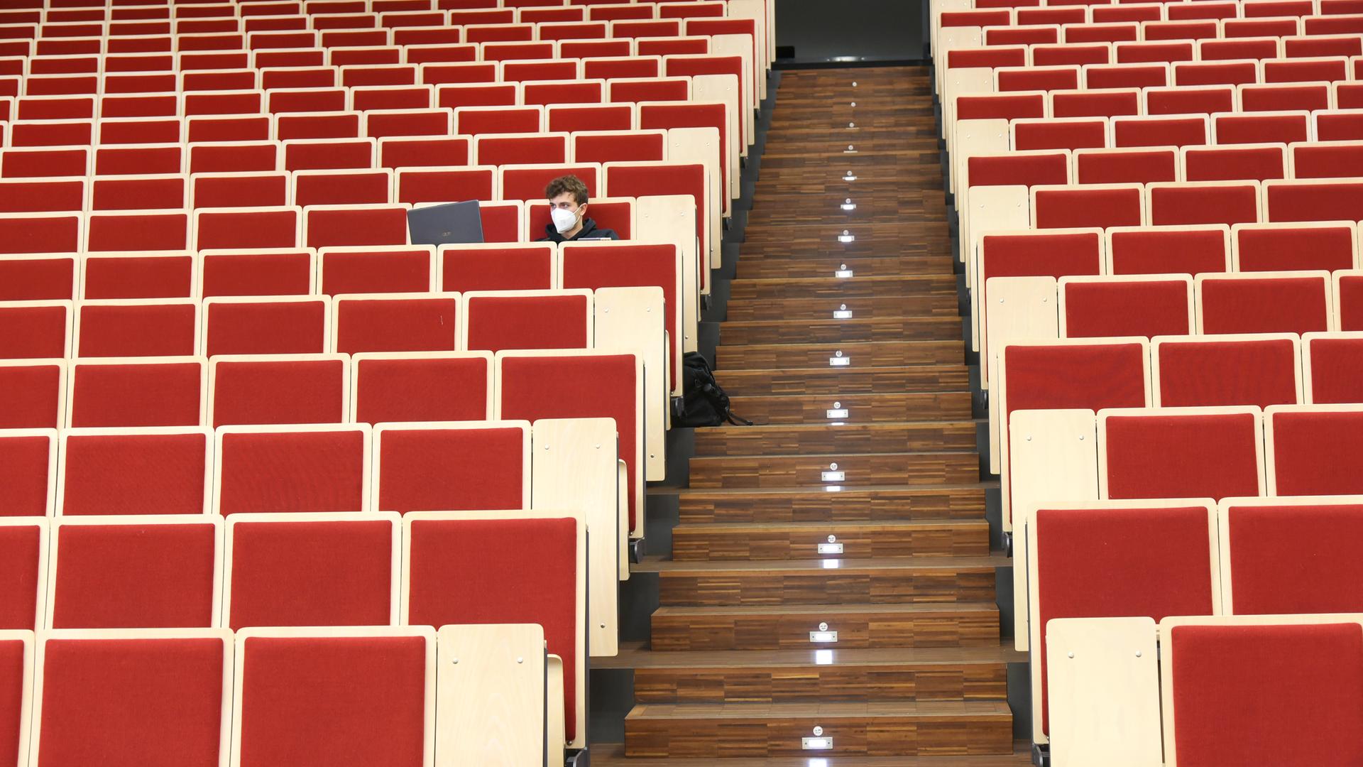 An der Universität Leipzig sitzt ein Informatikstudent bei einer digitalen Vorlesung allein im Auditorium maximum. Er blickt auf seinen Laptop, die Stuhlreihen sind sonst leer. An der Universität Leipzig sitzt ein Informatikstudent bei einer digitalen Vorlesung allein im Auditorium maximum. Er blickt auf seinen Laptop, die Stuhlreihen sind sonst leer.