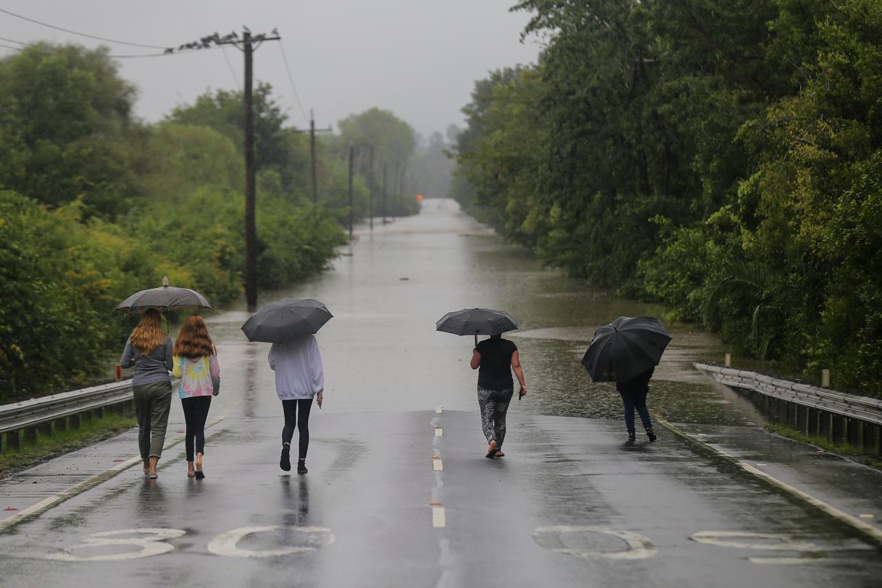 Menschen mit Regenschirmen laufen in Richtung einer überfluteten Straße in Richmond, nordwestlich von Sydney.
