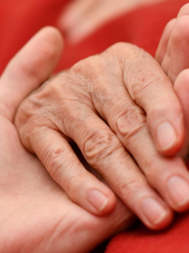 Sterbehilfe - Ibsens literarisches Drama "Gespenster" prallt auf eine persönliche Geschichte. Zu sehen: Zwei Hände halten ineinander auf einer roten Decke. 