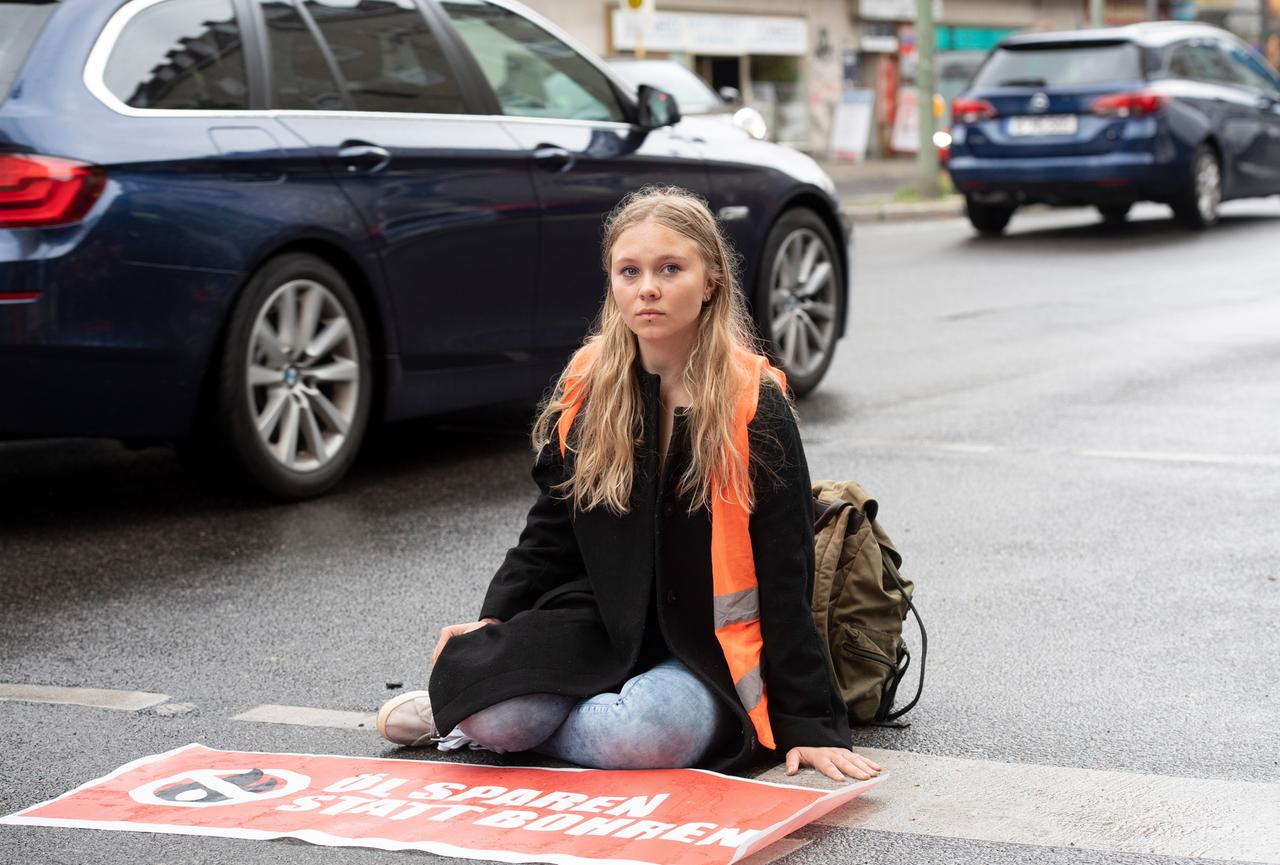 Klebeprotestlerin Aimée van Baalen sitzt festgeklebt auf einer Straße. Klebeprotestlerin Aimée van Baalen sitzt festgeklebt auf einer Straße.