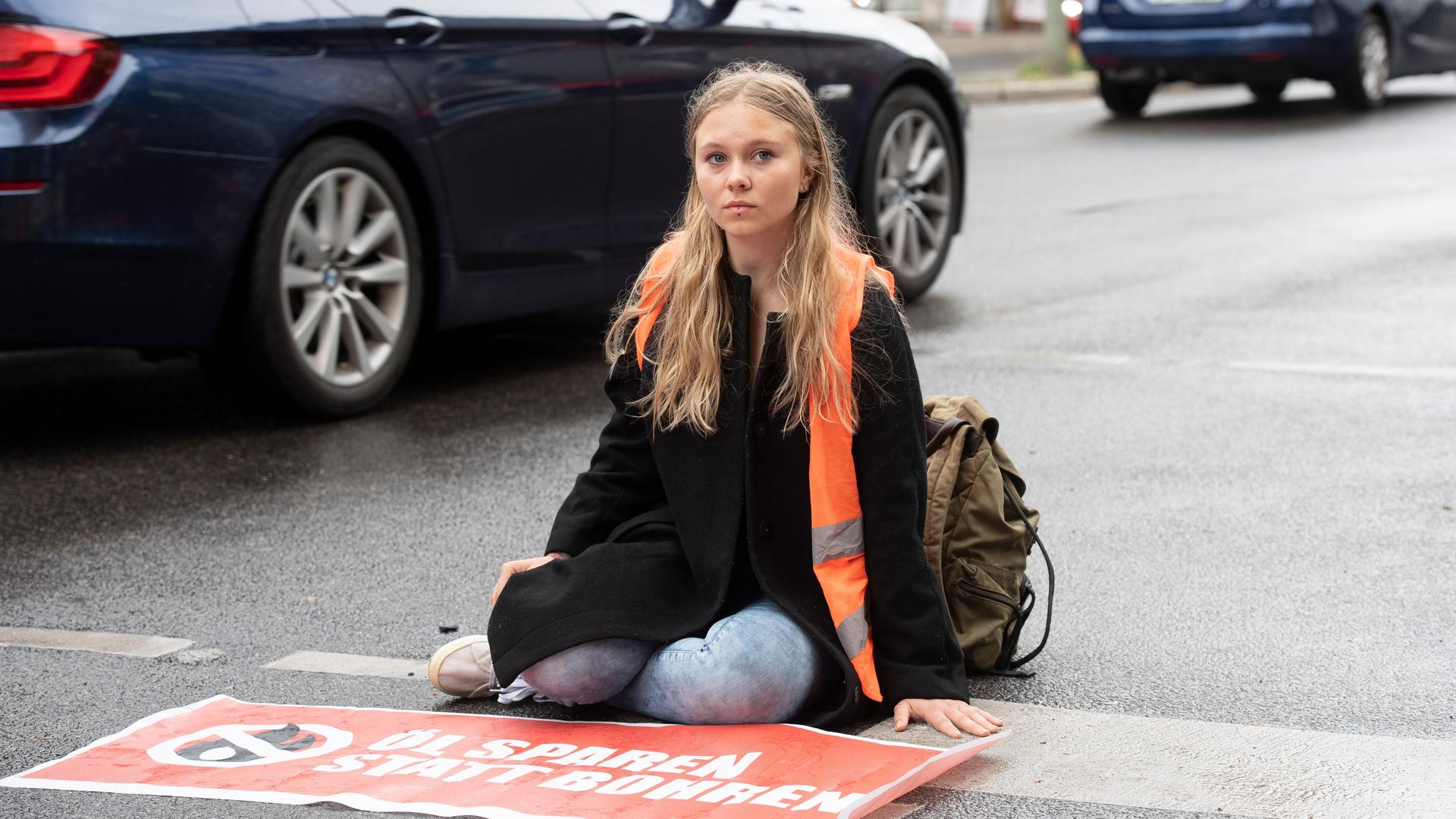 Klebeprotestlerin Aimée van Baalen sitzt festgeklebt auf einer Straße. Klebeprotestlerin Aimée van Baalen sitzt festgeklebt auf einer Straße.