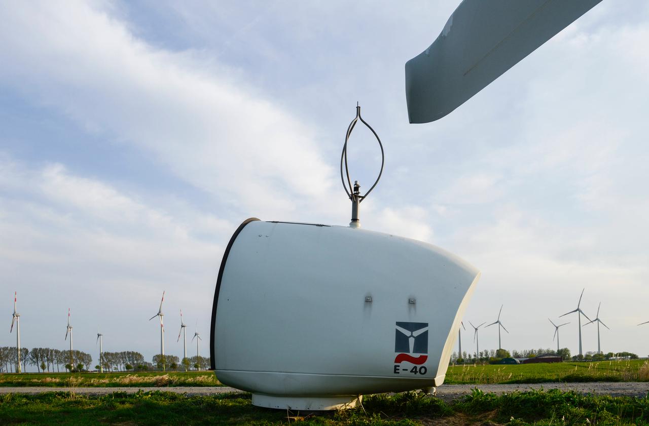 Ein kleine E-40 Windturbine liegt auf einer Grasfläche. Im Hintergrund stehen Windräder.