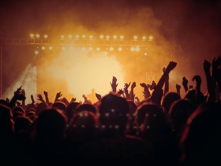 Bild einer Menschenmenge beim Konzert - das Publikum ist in gelbes Licht getaucht