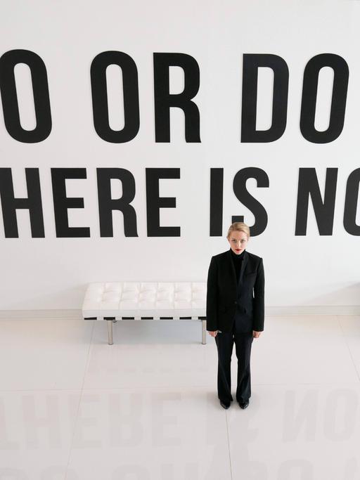 Im Still aus "The Dropout" steht Amanda Seyfried in schwarzen Klamotten vor einer Wand mit dem Yoda-Zitat: "Do or do not. There is no try." 
