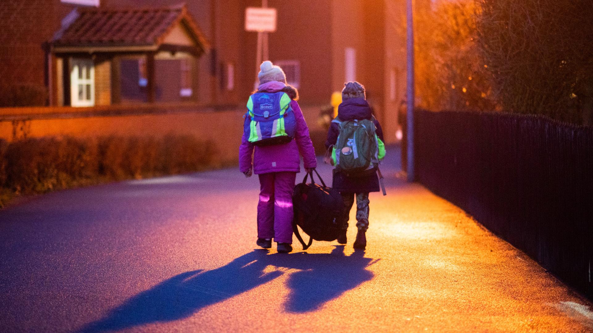Zwei Schüler gehen am frühen Morgen auf dem Schulweg zu ihrer Grundschule in der Region Hannover. 