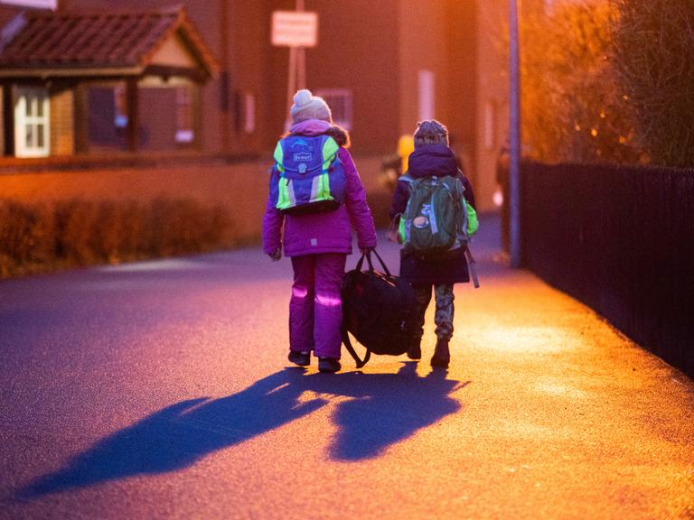 Zwei Schüler gehen am frühen Morgen auf dem Schulweg zu ihrer Grundschule in der Region Hannover. 