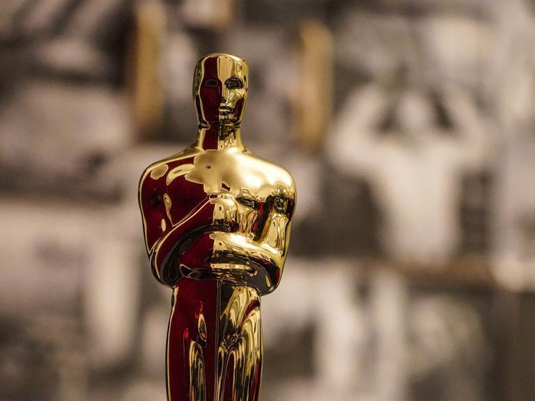 Blick auf einen Oscar, die goldene Statue mit glattem Kopf und Händen vor der Brust.