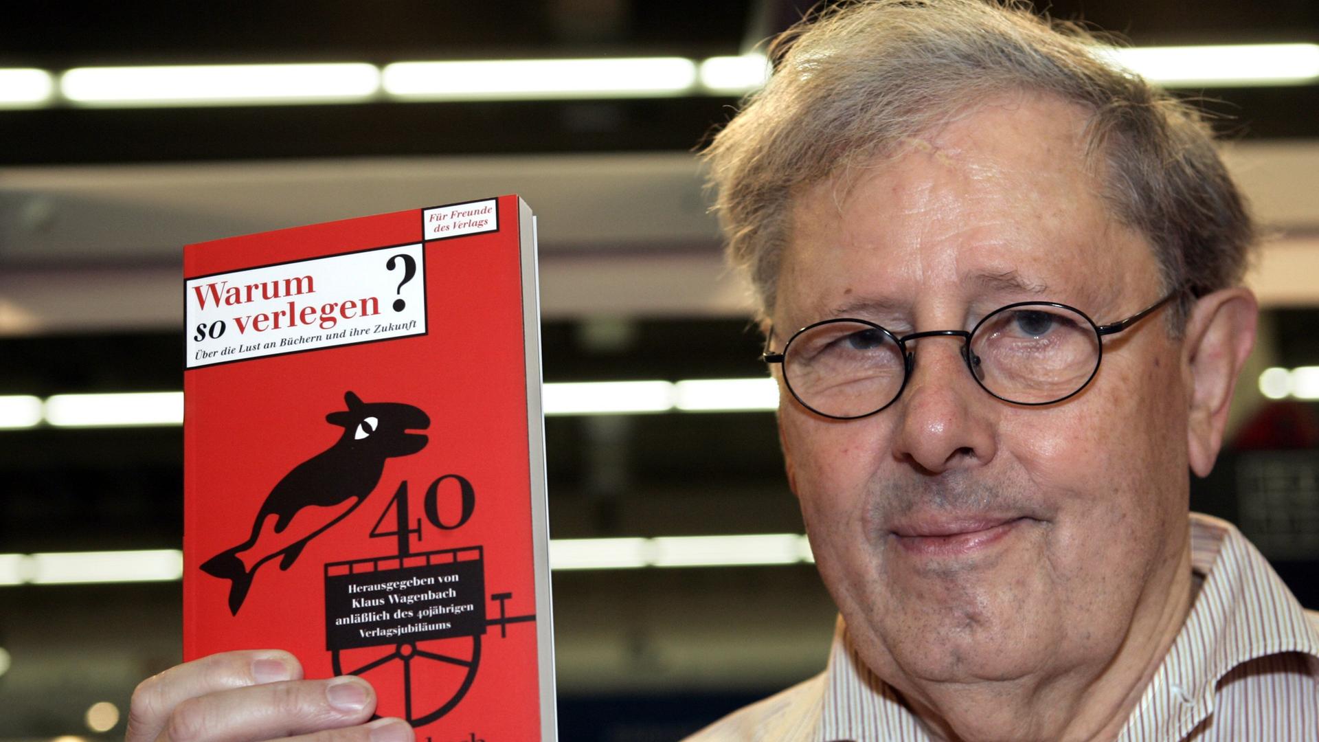 Der Verleger Klaus Wagenbach hält ein rotes Buch hoch