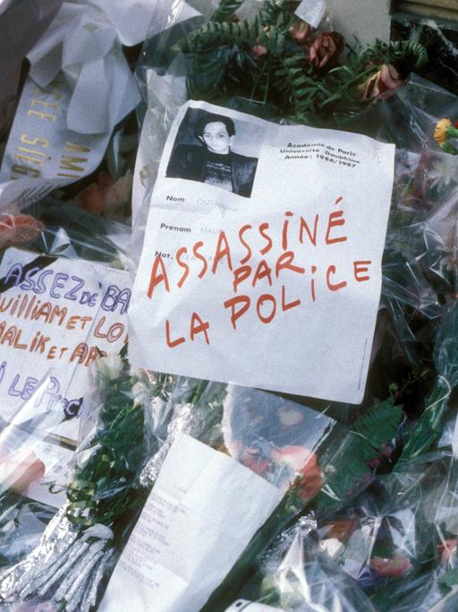 Blumen und beschriftete Zettel zum Gedenken an Malik Oussekine