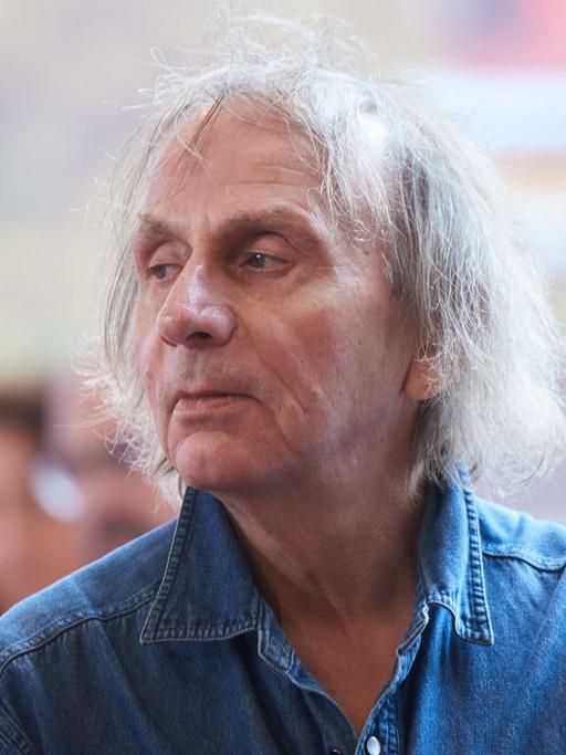 Michel Houellebecq sitzt im Jahr 2020 bei einer Premiere auf einem Stuhl und schaut zur Seite.