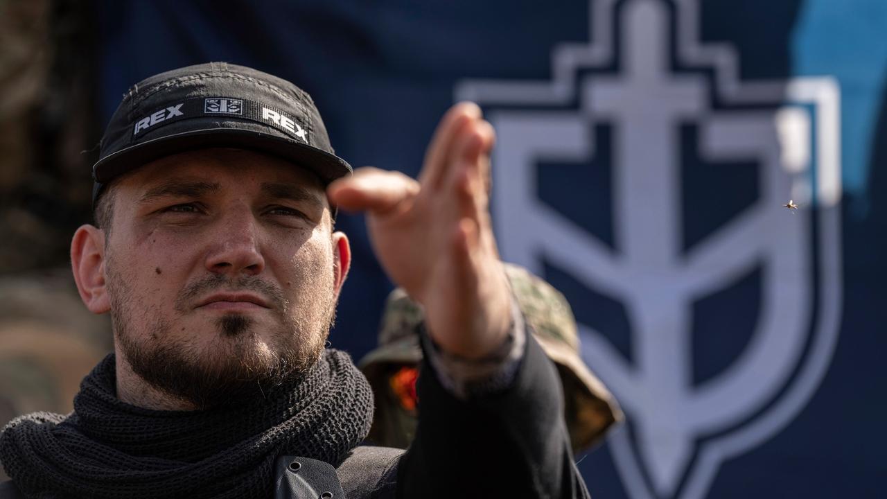 Denis Kapustin, Kommandeur des Russischen Freiwilligenkorps (RVC), vor einer Fahne seiner Einheit. Seine Schirmmütze trägt den Schriftzug "Rex".
