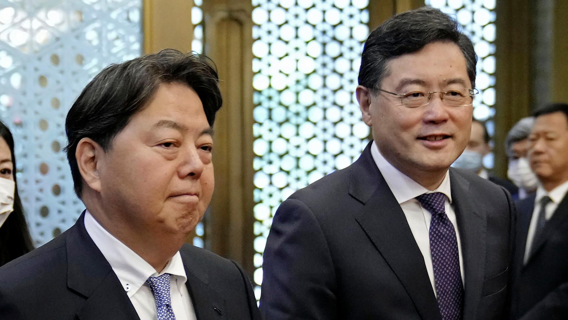 Die Außenminister Japans und Chinas stehen nebeneinander. Beide lächeln verhalten. Die Außenminister Japans und Chinas stehen nebeneinander. Beide lächeln verhalten.