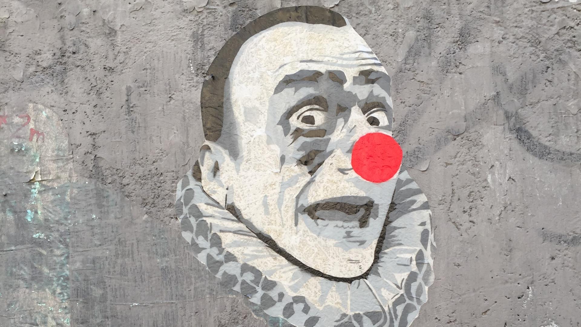Eine Straßenzeichnung zeigt ein Clownsgesicht in schwarz-weißen Farben und einer knallroten, kugelrunden Nase. Eine Straßenzeichnung zeigt ein Clownsgesicht in schwarz-weißen Farben und einer knallroten, kugelrunden Nase.