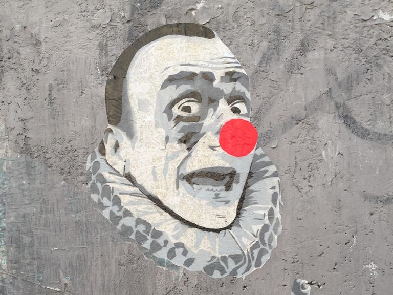Eine Straßenzeichnung zeigt ein Clownsgesicht in schwarz-weißen Farben und einer knallroten, kugelrunden Nase.