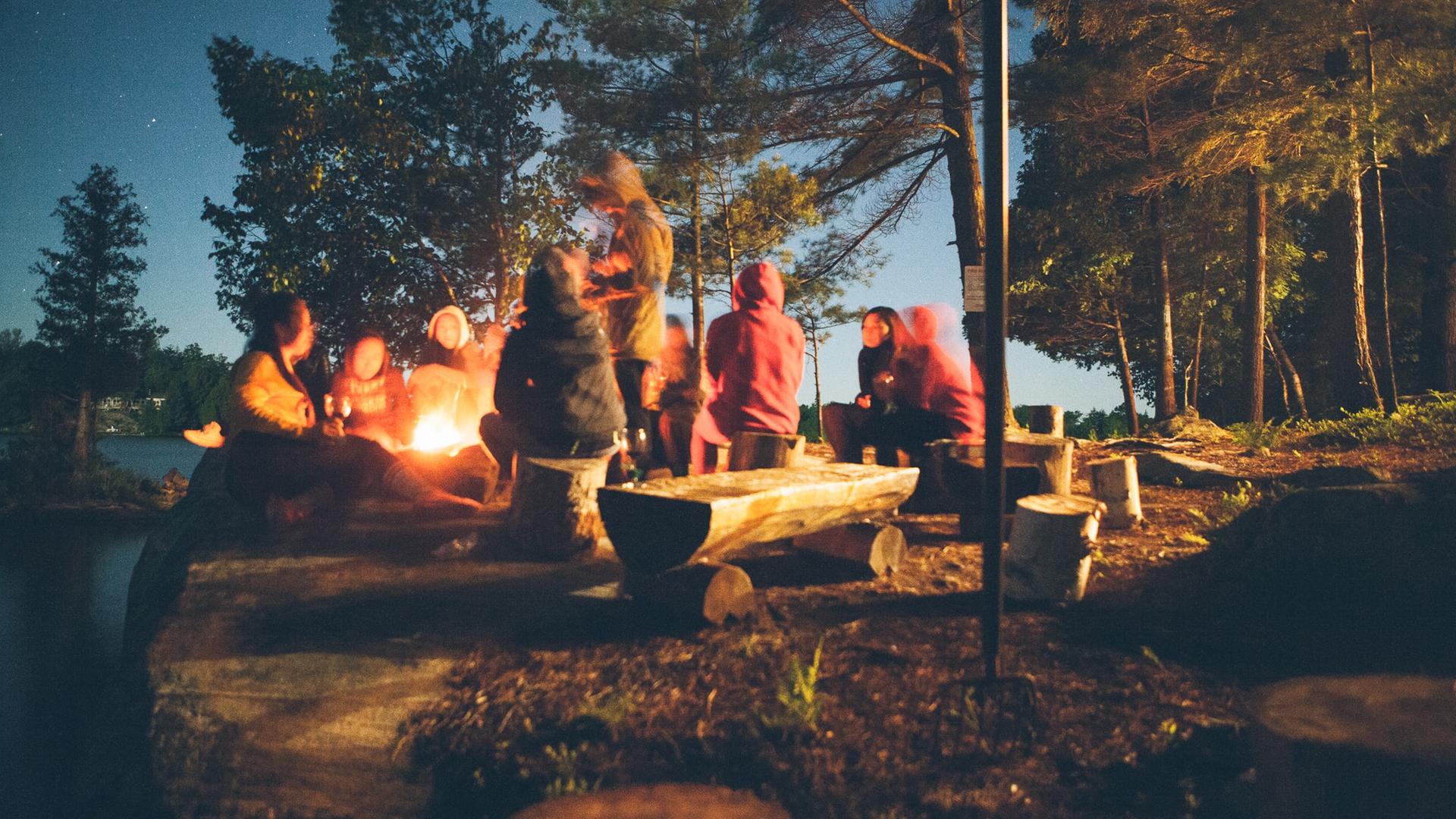 Eine Gruppe von Menschen sitzen an einem Lagerfeuer. Eine Gruppe von Menschen sitzen an einem Lagerfeuer.