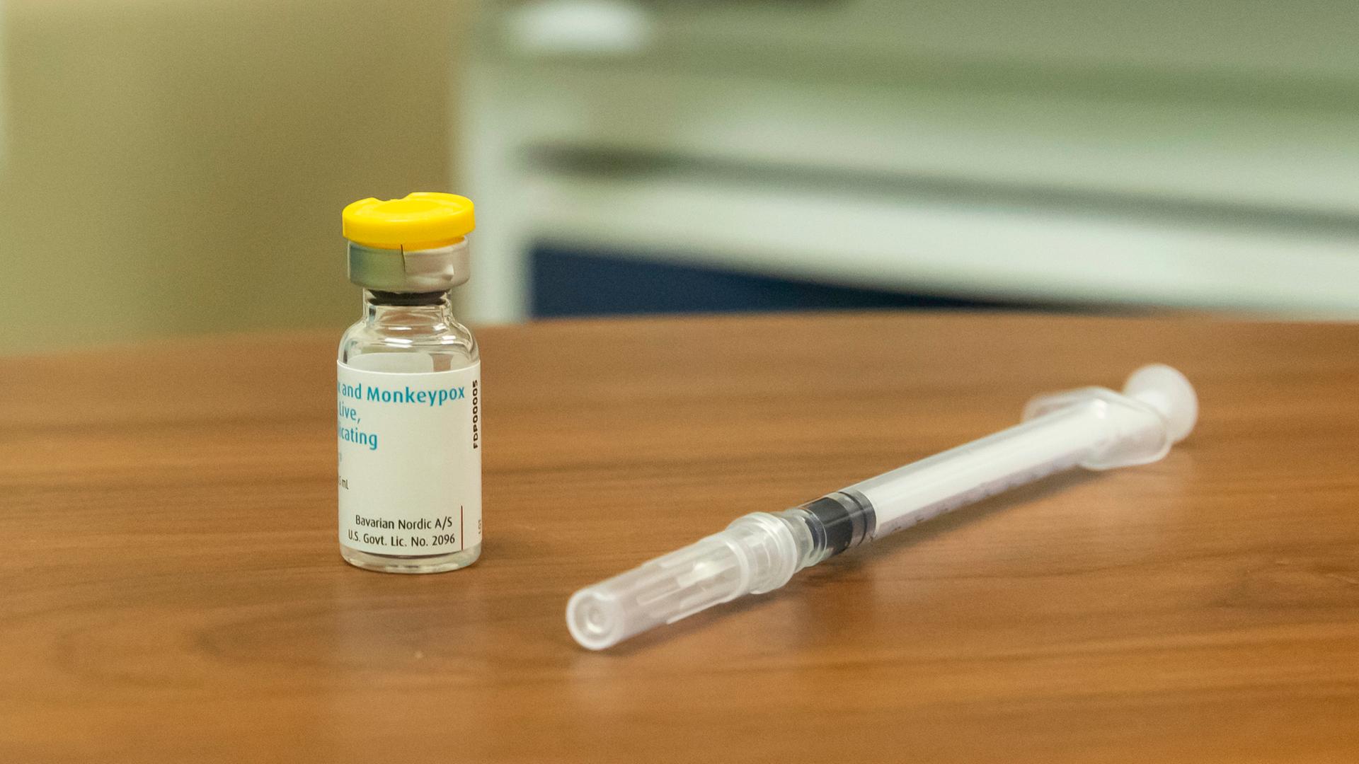 Mpox-Impfstoff und Spritze auf einem Holztisch