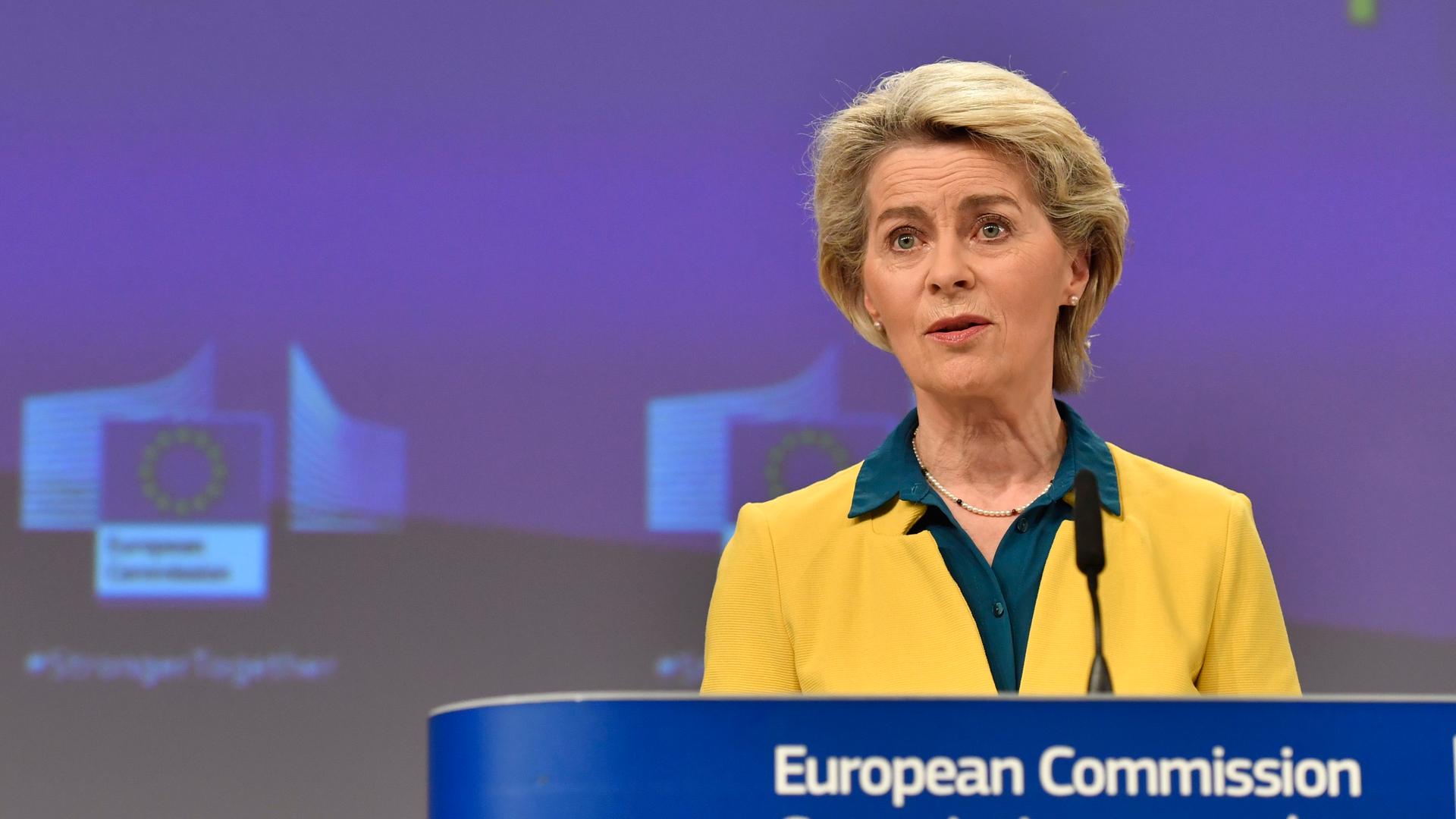 EU-Kommissionspräsidentin Ursula von der Leyen in gelbem Sakko vor einem blauen Hintergrund mit der Aufschrift EU Membership