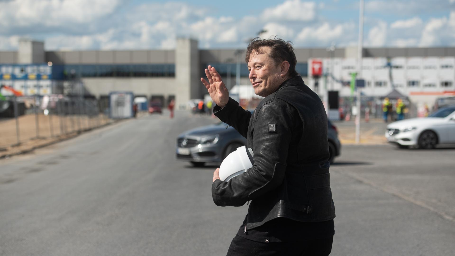 Tesla-Chef Elon Musk mit einem Baustellenhelm in der Hand steht vor der Tesla-Fabrik in Grünheide Tesla-Chef Elon Musk mit einem Baustellenhelm in der Hand steht vor der Tesla-Fabrik in Grünheide
