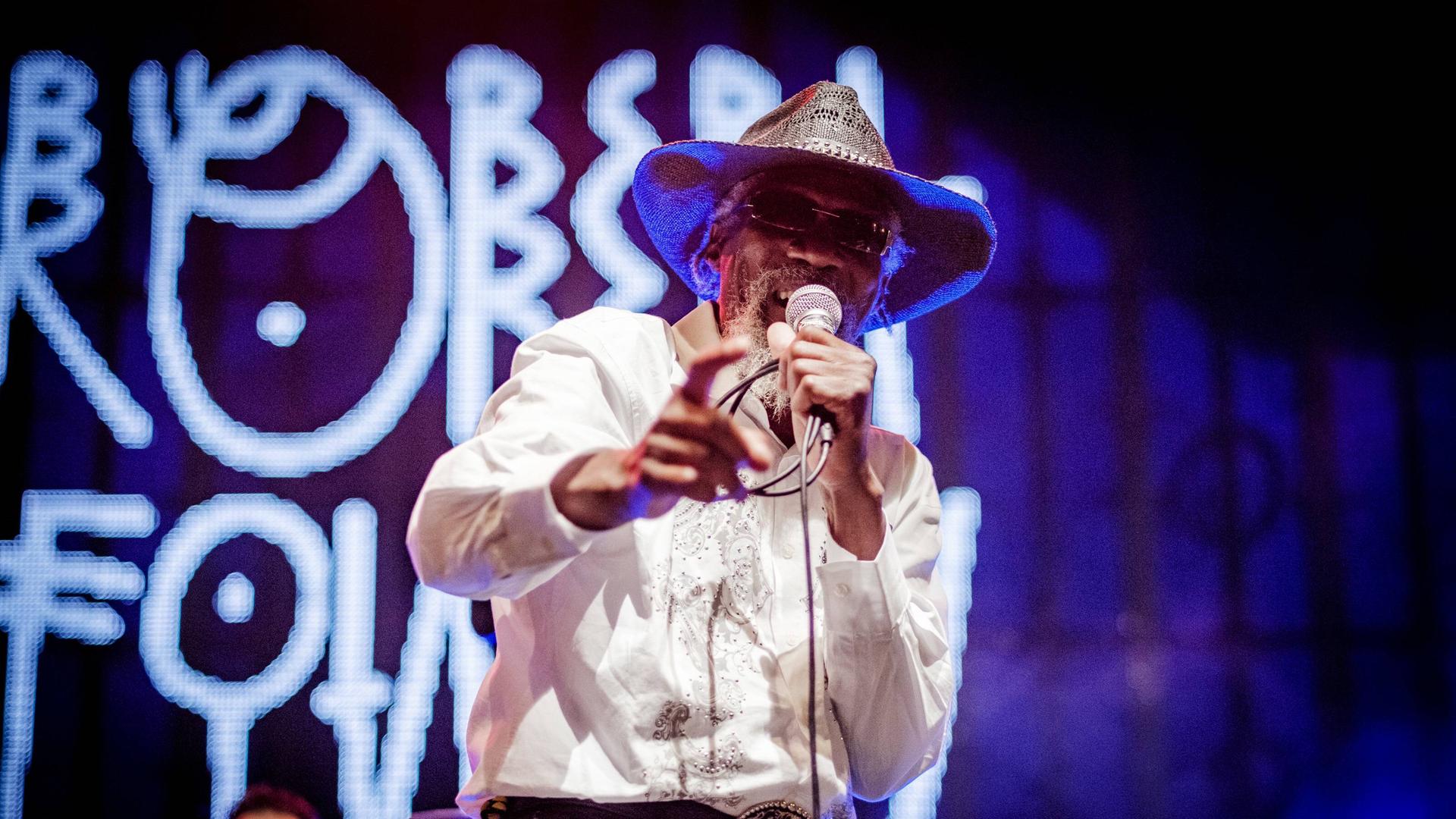 Robert Finley steht 2018 auf einer Bühne des Musicas do Mundo Festivals mit Hut und dunkler Brille. Robert Finley steht 2018 auf einer Bühne des Musicas do Mundo Festivals mit Hut und dunkler Brille.