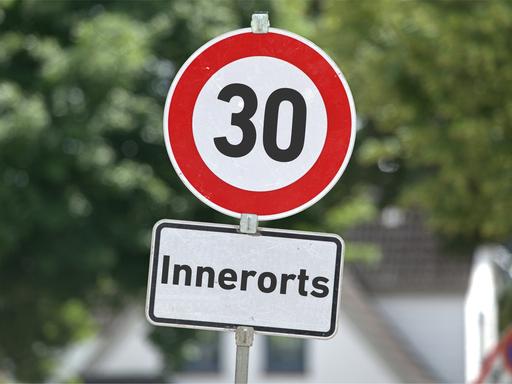 [M] Verkehrszeichen 274-30 in runder Form mit der Aufschrift "30" sowie ein Zusatzschild mit der Aufschrift: "Innerorts" an einem Schildermast. Foto mit Composing als Symbolbild für lauter werdende Forderungen für ein generelles Tempolimit von 30 km/h in Ortschaften.