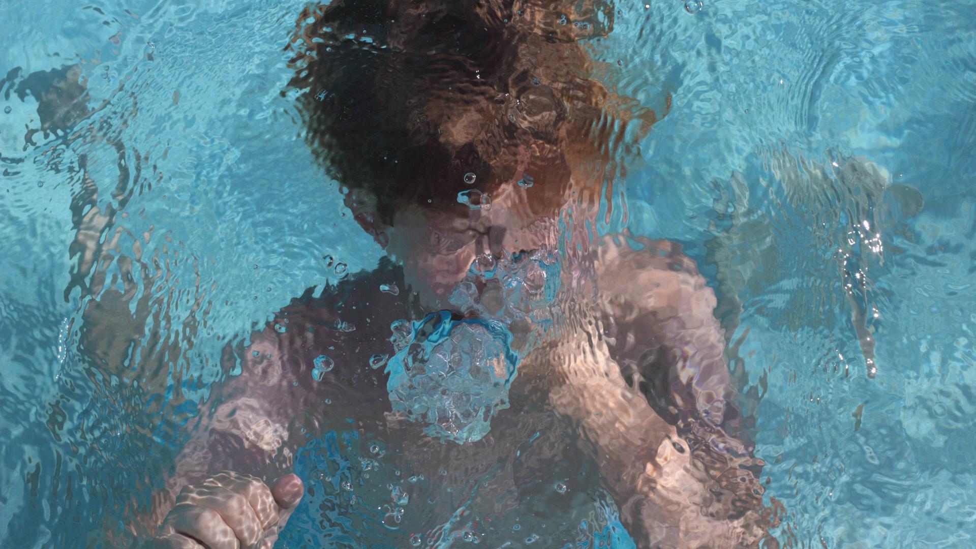 Ein Kind schwimmt unter Wasser in einem Pool. Ein Kind schwimmt unter Wasser in einem Pool.
