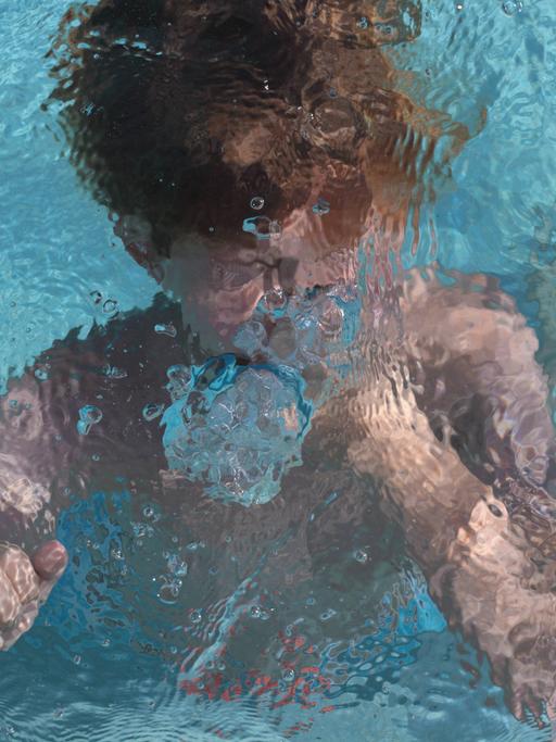 Ein Kind schwimmt unter Wasser in einem Pool.