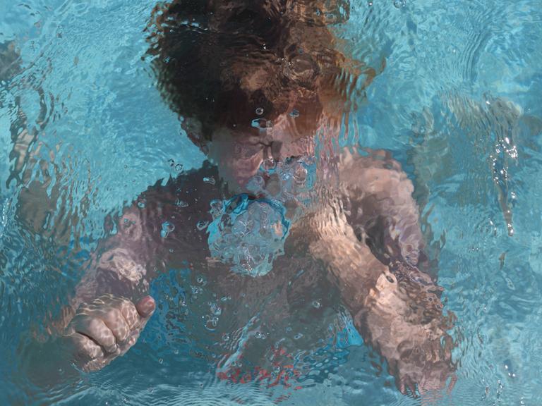 Ein Kind schwimmt unter Wasser in einem Pool.