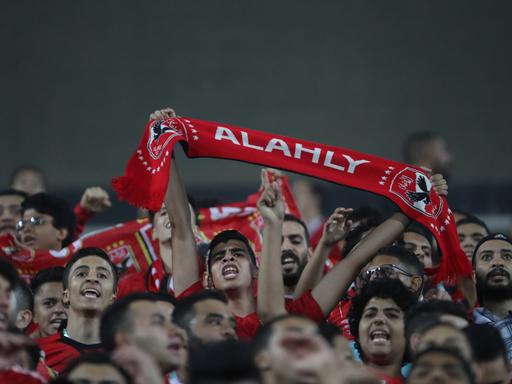 Ägyptische Fußballfans singen im Stadion, einer hält einen Schal seines Vereins Al Ahly hoch