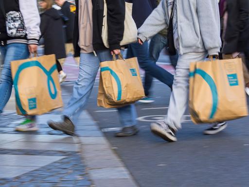 Passanten tragen Einkaufstaschen beim Überqueren der Strasse