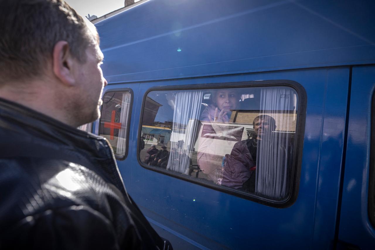Eine Frau verabschiedet sich in der ukrainischen Stadt Kramatorsk von ihrem Mann. Sie sitzt in einem Bus und winkt ihm durch die Scheibe zu.