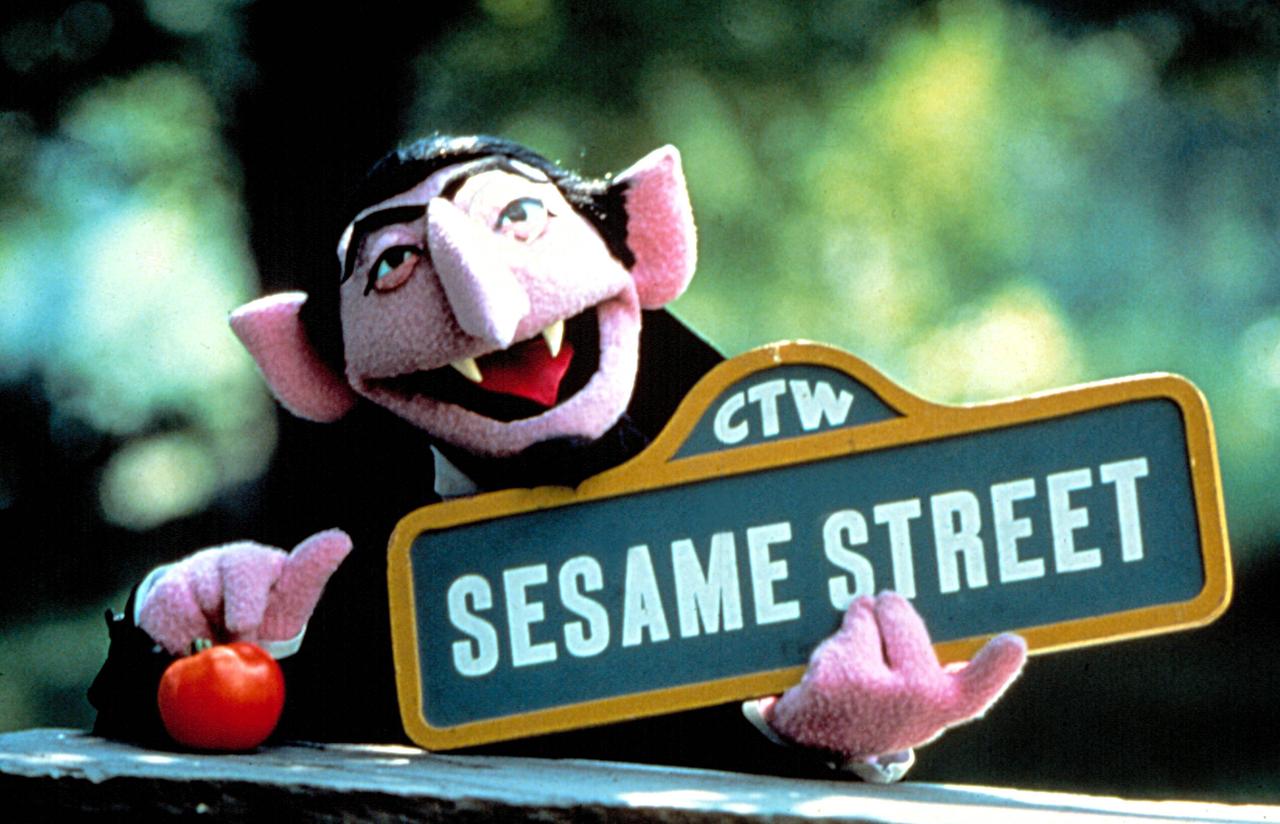Graf Zahl aus der Sesamstraße: Die Puppe sieht aus wie ein Vampir und trägt ein Straßenschild in der Hand.