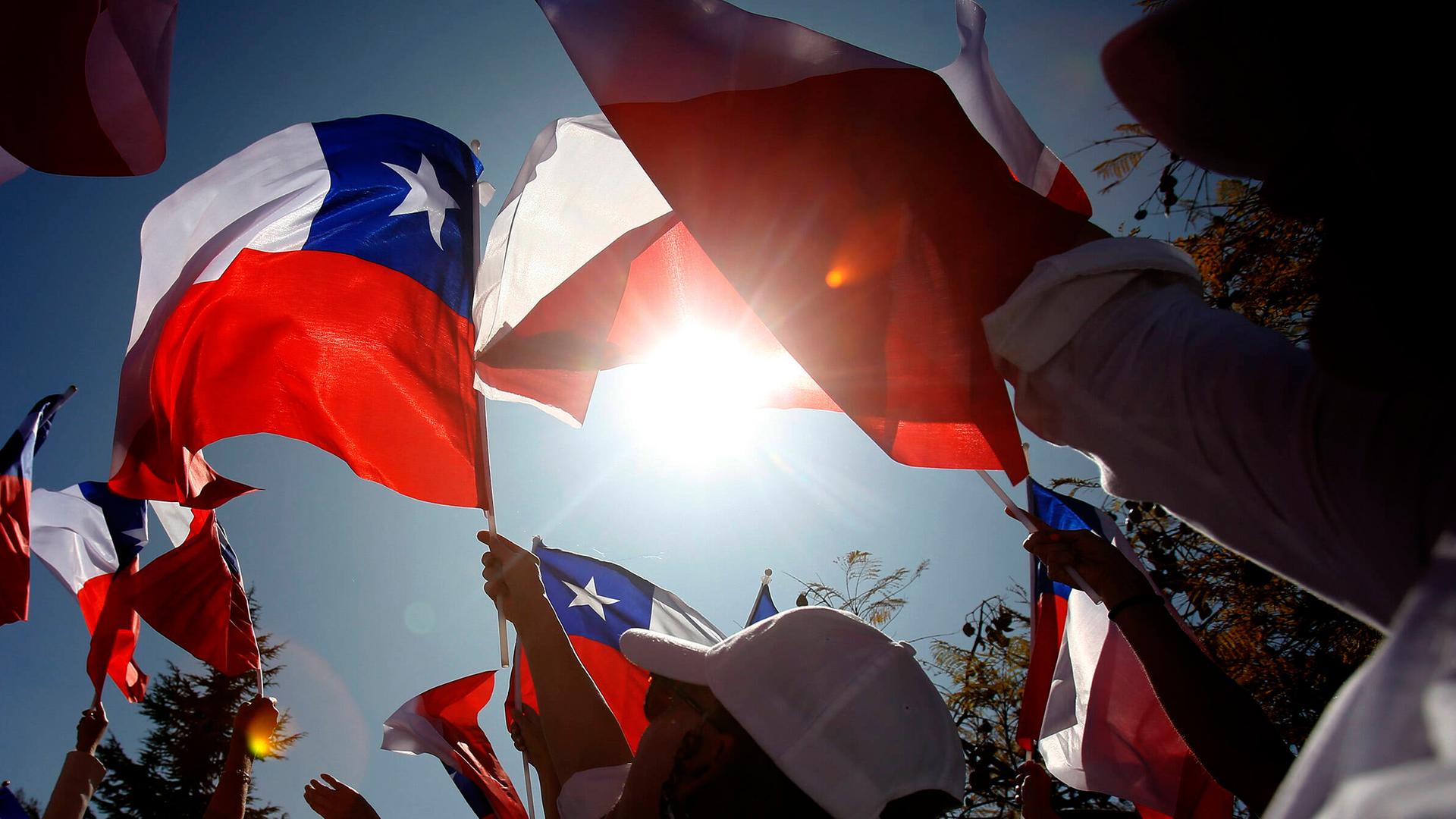 Viele Menschen treffen sich in Santiago mit ihren Flaggen, die sie der Sonne entgegen halten. Viele Menschen treffen sich in Santiago mit ihren Flaggen, die sie der Sonne entgegen halten.
