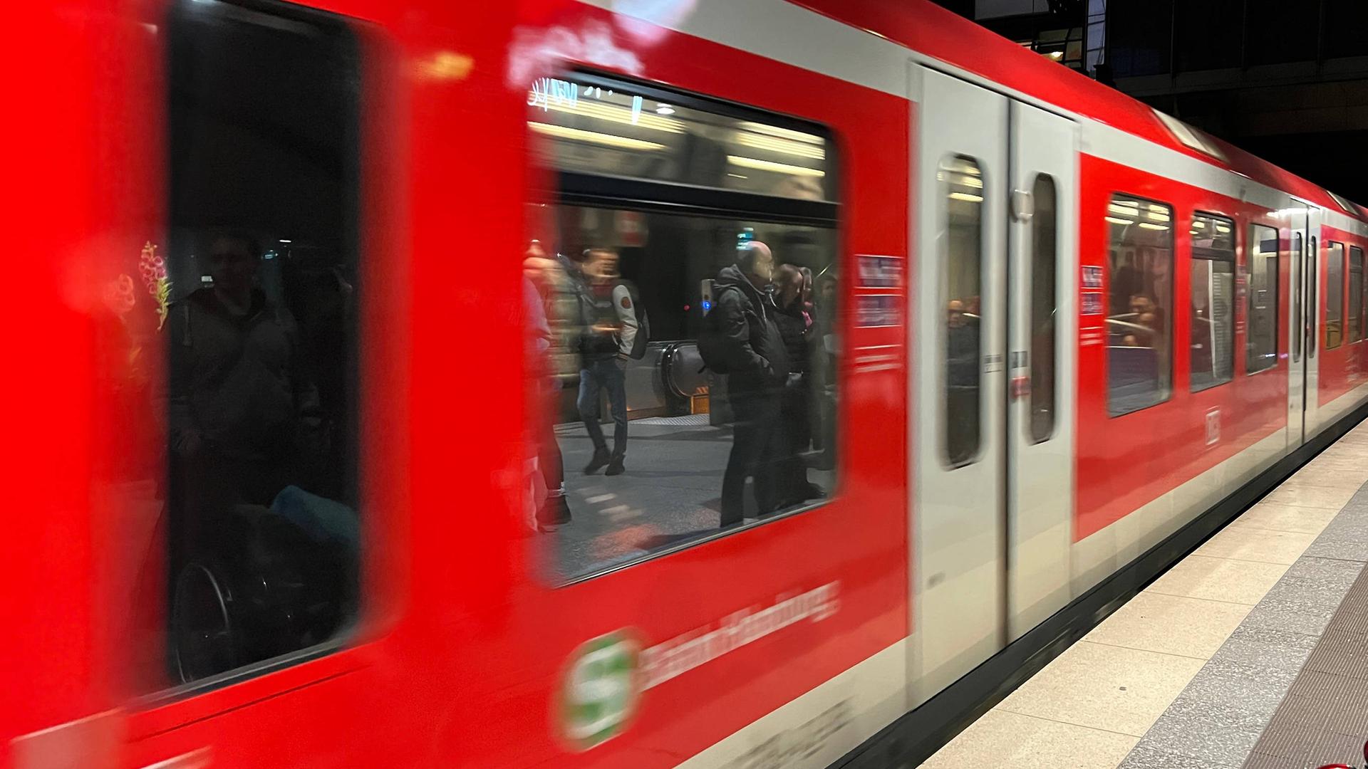 Eine rote S-Bahn fährt am Gleis ab.