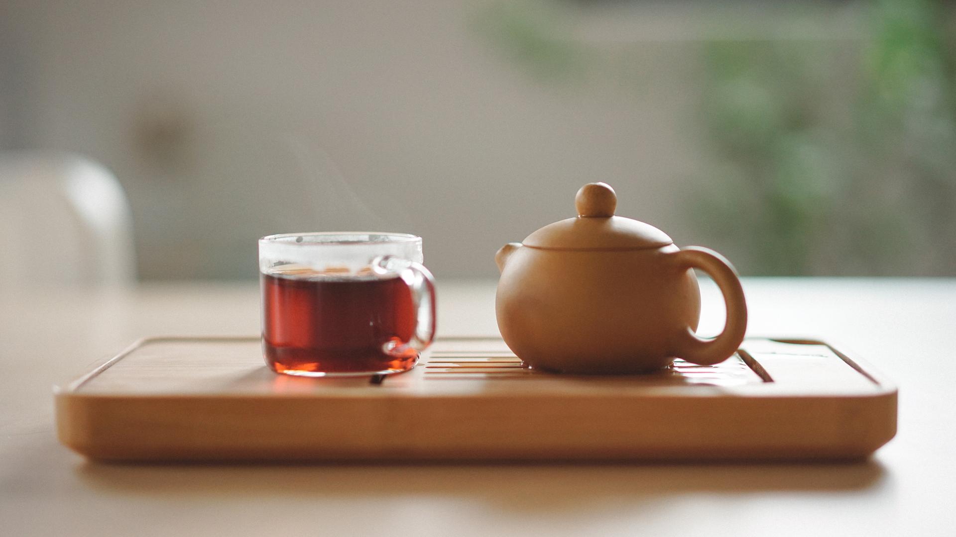 Eine Tasse Tee und eine Teekanne stehen auf einem Tablett. Eine Tasse Tee und eine Teekanne stehen auf einem Tablett.
