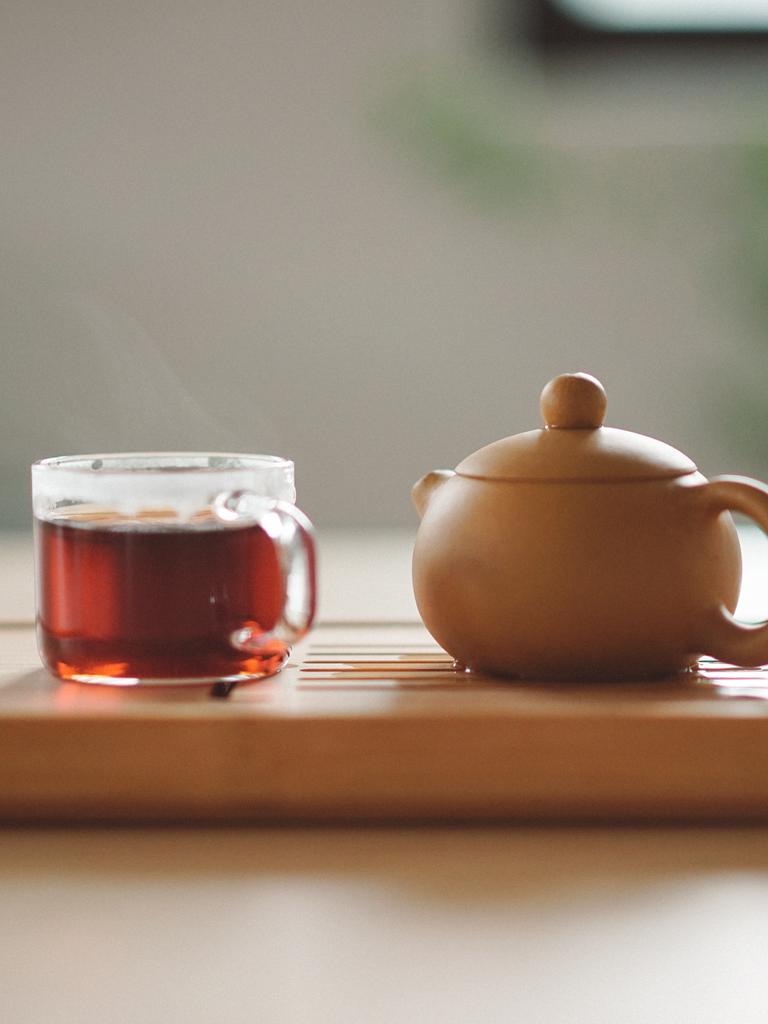 Eine Tasse Tee und eine Teekanne stehen auf einem Tablett.
