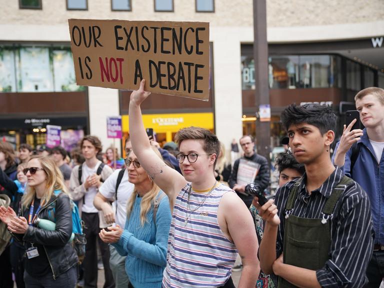 Die LGBTQ-Community protestiert gegen die Rede der Philosophin Kathleen Stock. Die Menschen halten Schilder hoch.